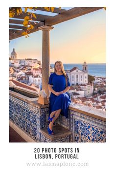 a woman in a blue dress is sitting on a balcony overlooking the ocean and buildings