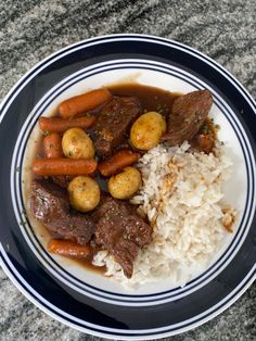 a white plate topped with rice and meat covered in gravy on top of a table