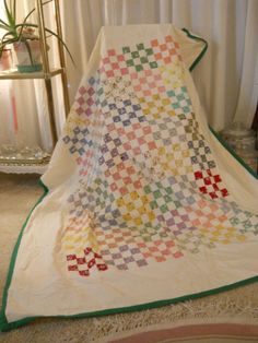 a quilted blanket sitting on top of a bed next to a mirror and potted plant