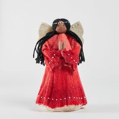 an angel figurine is dressed in red and holding her hands up to the side