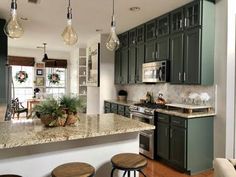 a large kitchen with green cabinets and marble counter tops, along with bar stools