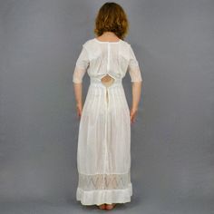 "Antique Edwardian white cotton lace lingerie dress. Styled with a square cut cotton neckline with short vertical pin tucks featuring a dainty floral net lace center inset along with lace shoulder bands extending to the waistline. Gathered center bust, 1/2 length lace trimmed dolman sleeves, wide banded nipped waistline and flowing floor length skirt with flattering vertical tuck seams and horizontal lace inset near hem. The dress closes up the back with hook and eyes. Label: None Content: Semi- Fitted Cotton Dress With Delicate Lace, Fitted Regency Victorian Dress For Daywear, Fitted Delicate Lace Dress For Daywear, White Victorian Dress With Fitted Bodice For Daywear, Vintage White Regency Dresses For Daywear, Vintage White Regency Style Dress For Daywear, Regency Style Daywear Dress With Broderie Anglaise, Regency Style Vintage White Day Dress, Fitted Prairie Dress With Lace Trim For Daywear