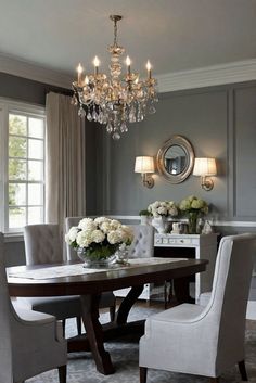 a dining room table with chairs and chandelier in the corner, surrounded by white flowers