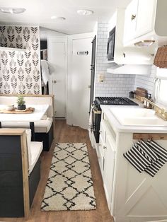 a small kitchen with white cabinets and black accents on the countertops, along with a rug