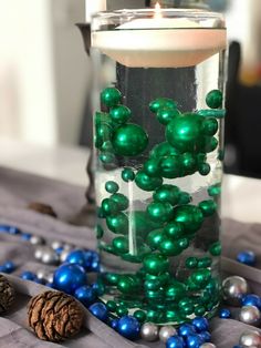 a candle that is sitting on a table with beads in it and some other decorations around it