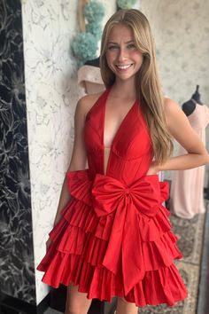 Crafted from high-quality taffeta, this dress features a sophisticated A-line shape in a bold red hue. The halter neck and tiered ruffle skirt create a playful and feminine look, while the above-knee length adds a touch of elegance. Completed with a charming bow detail at the waist and a convenient zip-up back, this dress is the perfect addition to your wardrobe. SKU: 3725 Taffeta material A-line silhouette Red color Halter neck Tiered ruffle skirt Above knee length Bow on the waist Zip-up back Red Satin Ruffled Dress, Red Satin Dress With Ruffles, Ruffle Halter Dress For Wedding, Taffeta Prom Dress With Ruffles, Red Party Dress With Ruffled Skirt, Elegant Tiered Halter Dress For Party, Red Ruffle Dress For Party, Tiered Halter Dress For Party, Tiered Ruffle Halter Dress For Party