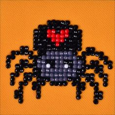 an image of a cross stitch bead pattern with a black and red spider on it