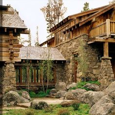 an old stone building with wooden balconies on the roof and windows is surrounded by large rocks