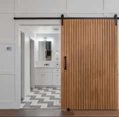 an open wooden sliding door in a white bathroom