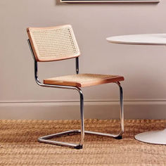 a chair sitting in front of a table with a painting on the wall behind it