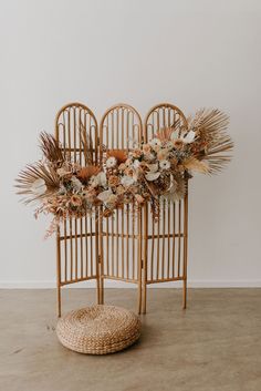 an arrangement of dried flowers and plants in wicker chairs