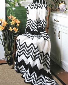 a chair with a blanket on it in front of a potted plant and flowers