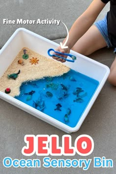 The perfect sensory play idea for toddlers. Let them have sticky messy fun with this easy to make ocean themed sensory bin using Jello! All you need is a container, blue jello, and some small sea creatures. Kids can squish the jello and use tongs to find the sea animals. This is a great way to introduce different senses to babies too! And the sensory bin is taste safe. Perfect for young kids. Jello Sensory Bin, Jello Sensory Play, Ocean Jello, Sensory Play For Toddlers, Kids Sensory Activities, Sensory Bin Play, Toddler Sensory Bins, Blue Jello, Baby Sensory Play