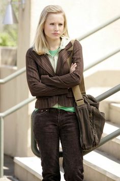 a woman with her arms crossed standing in front of some stairs