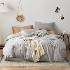 an unmade bed with grey sheets and pillows