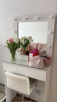 a white vanity with flowers and cosmetics on it