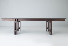 a long wooden table sitting on top of a white floor next to a gray wall