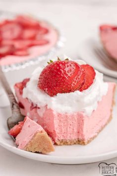 a slice of strawberry cheesecake on a white plate with a fork and two pies in the background