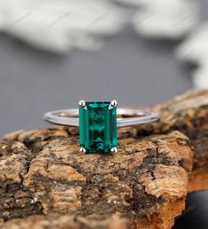 an emerald ring sitting on top of a rock