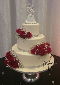 a three tiered wedding cake with red roses