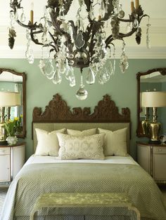 a bedroom with a chandelier hanging from the ceiling and pillows on the bed