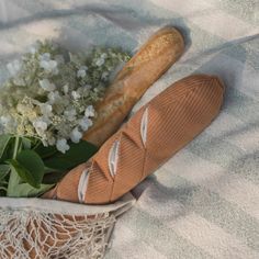 a loaf of bread sitting on top of a blanket next to flowers and a baguette