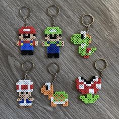 four pixel keychains with mario and luigi on them, all made out of perler beads