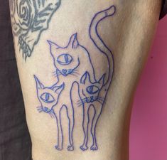 a tattoo on the leg of a person with two cats and a butterfly in the background