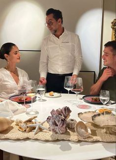 three people sitting at a table with wine glasses