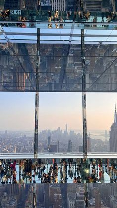 many people are standing on the glass walkway above the cityscape and skyscrapers