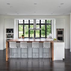 a large kitchen with an island in the middle and three stools on each side