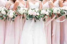 a group of women standing next to each other wearing pink dresses and holding bouquets