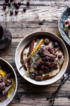 two bowls filled with food sitting on top of a wooden table next to utensils