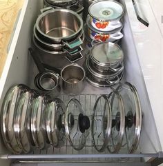 an open drawer filled with lots of different types of pots and pans on top of each other