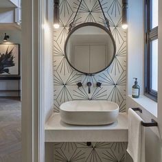 a white sink sitting under a bathroom mirror next to a wall mounted faucet