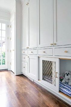 a dog bed in the middle of a room with white cabinets and wood flooring