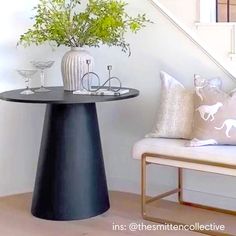 a black table sitting under a stair case next to a white bench with flowers on it