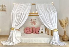 a bed with white drapes and pink pillows