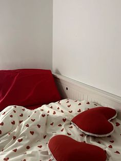 a bed with red pillows on it in a room that has white walls and flooring