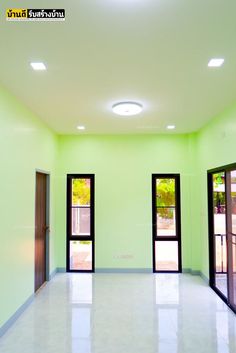 an empty room with three doors and two windows in the center is lit by recessed lights