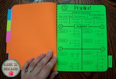 a hand is holding an orange notebook with numbers on it