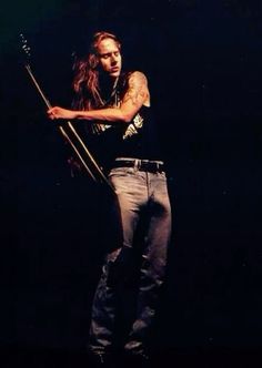 a man with long hair holding a stick in his right hand while standing on stage