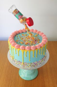 a cake with sprinkles and icing being poured onto it on a table