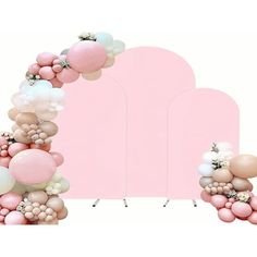 an arch made out of balloons and other items on a white background with a pink backdrop