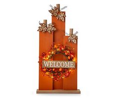 an orange welcome sign with a wreath on it and snowflakes hanging from the top