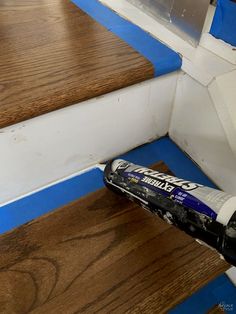 a close up of a paint roller on some wood steps with blue tape around it