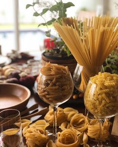 a table topped with lots of pasta and wine glasses filled with noodles on top of it