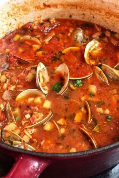 a pot filled with soup and clams on top of a stove