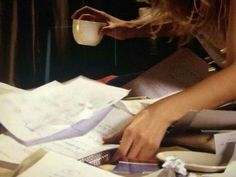 a woman is holding a cup over papers