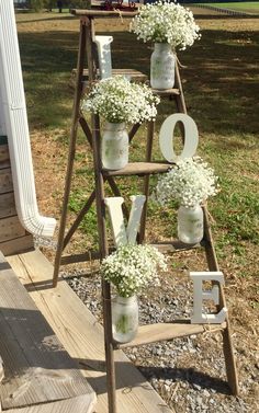 an old ladder is decorated with mason jars and baby's breath flowers to spell out the word love